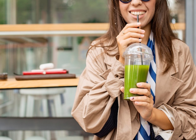 Foto gratuita mujer feliz bebiendo batido verde