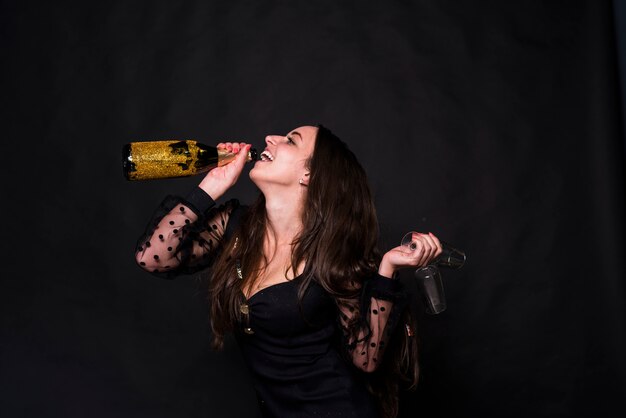 Mujer feliz bebiendo champán de botella
