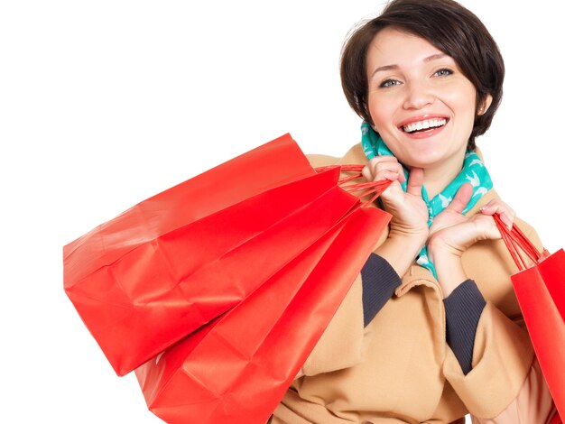 Mujer feliz con bolsas de compras en abrigo beige otoño con pañuelo verde aislado en blanco