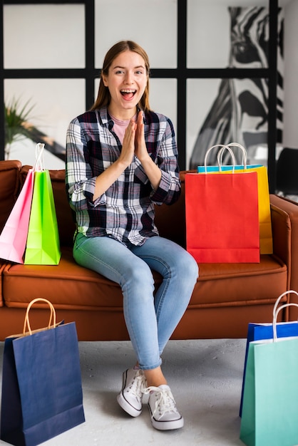 Mujer feliz con bolsas sentado en el sofá