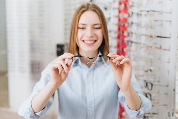 Mujer feliz buscando gafas nuevas en óptico