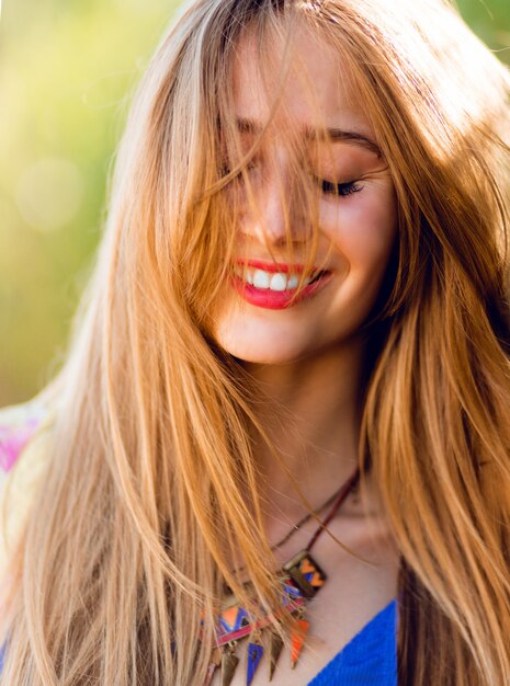 mujer feliz con cabello rubio ventoso y ojos cerrados