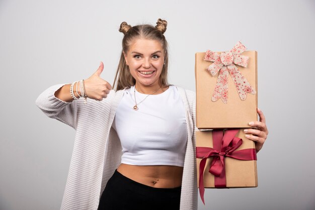 Mujer feliz con cajas de regalo dando pulgares.