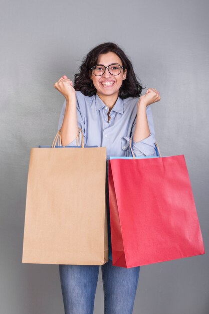 Mujer feliz en camisa con bolsas de compras