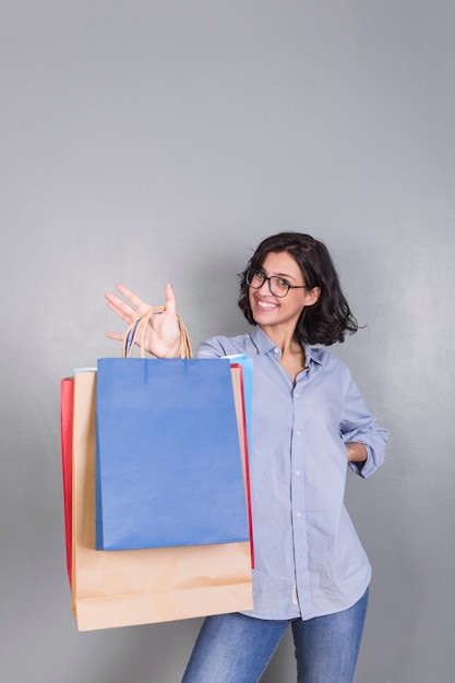 Foto gratuita mujer feliz en camisa mostrando bolsas de compras