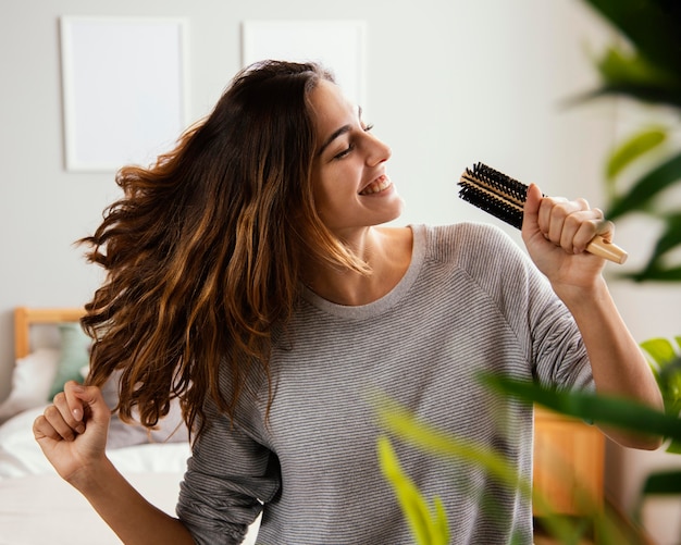 Foto gratuita mujer feliz cantando en cepillo para el pelo en casa