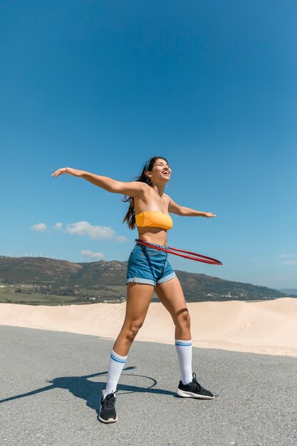 Mujer feliz en carretera girando aro de hula