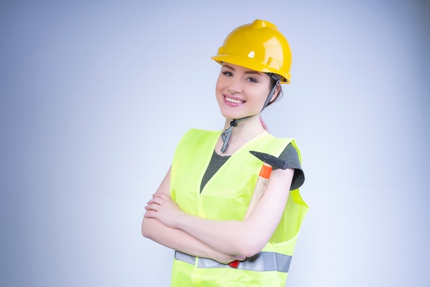 Mujer feliz en un casco amarillo y un chaleco de trabajo