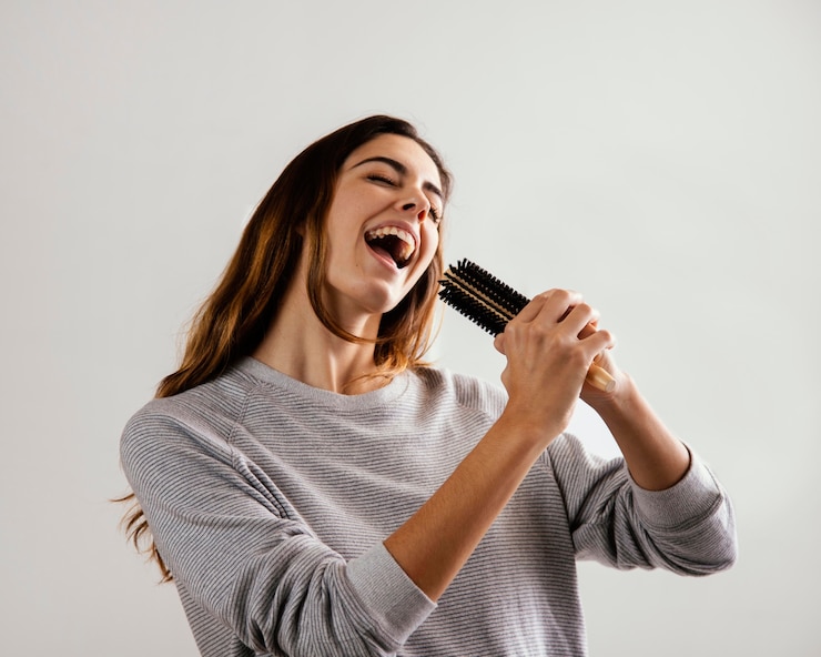 Foto gratuito mujer feliz con cepillo para el pelo como micrófono en casa