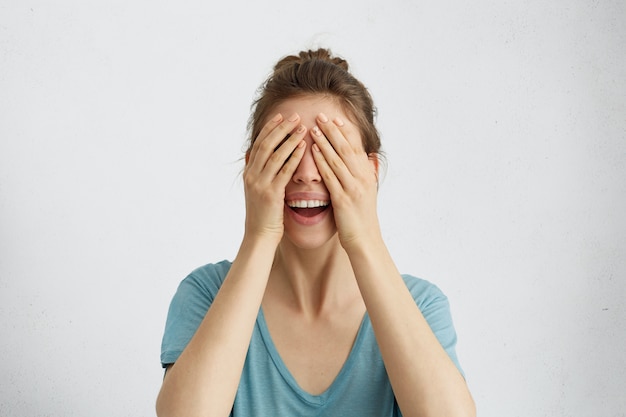 Foto gratuita mujer feliz cerrando los ojos con las manos yendo a ver sorpresa, de pie y sonriendo a la espera de algo maravilloso