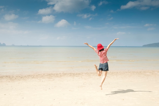 Mujer feliz en el cielo de la playa y de las nubes.