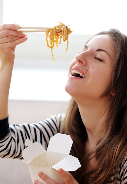 Mujer feliz comiendo fideos