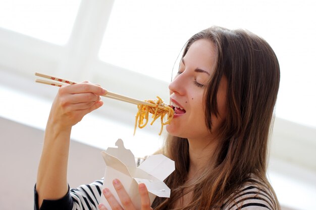 Mujer feliz comiendo fideos