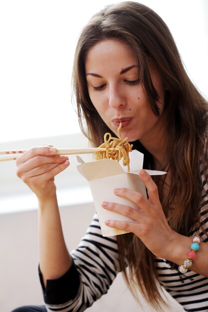 Mujer feliz comiendo fideos