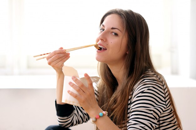 Mujer feliz comiendo fideos