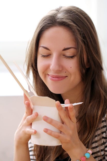 Mujer feliz comiendo fideos