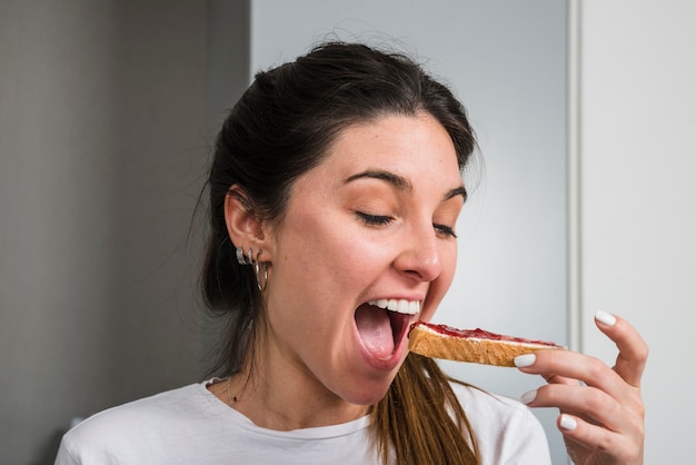 Mujer feliz comiendo mermelada y pan