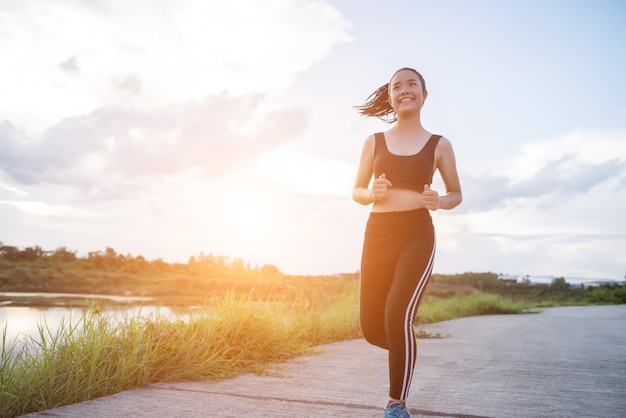 La mujer feliz del corredor corre en el ejercicio que activa del parque.