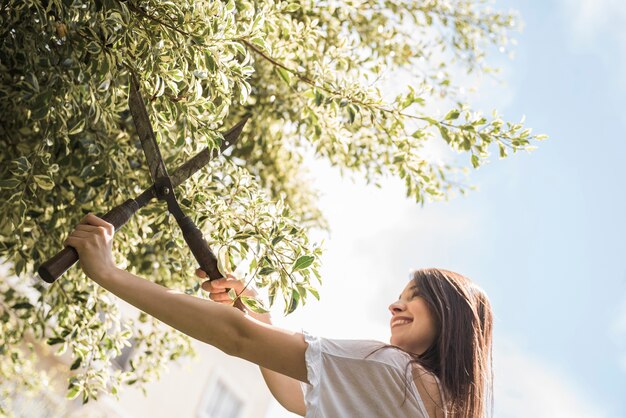 Mujer feliz cortando hojas con tijeras de jardinería