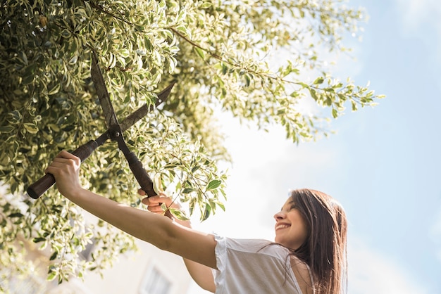 Mujer feliz cortando hojas con tijeras de jardinería