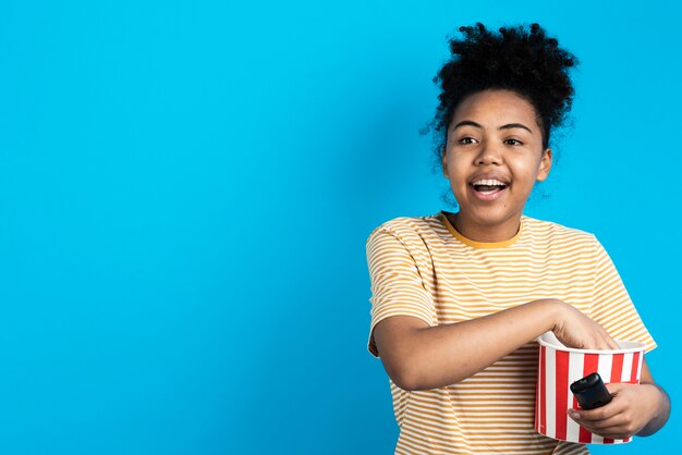 Mujer feliz con cubo de palomitas de maíz y control remoto