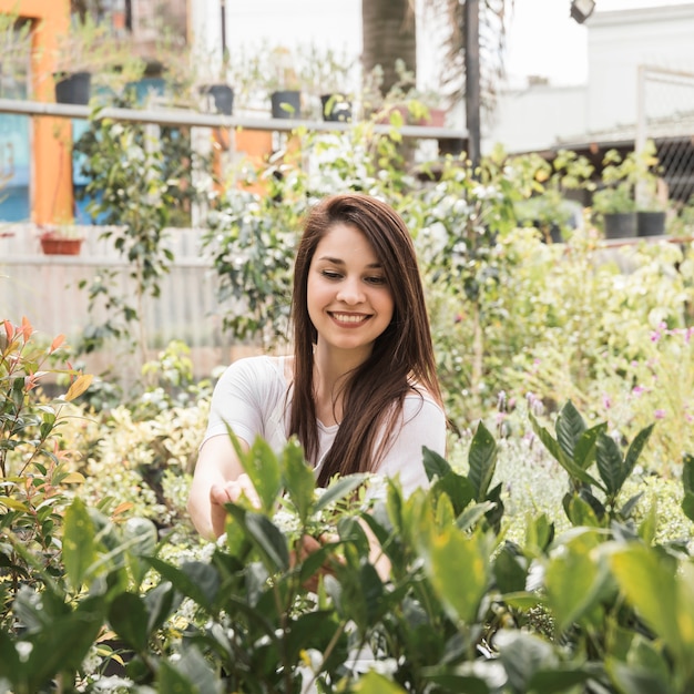 Mujer feliz cuidando plantas en invernadero