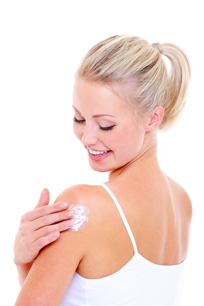 Mujer feliz cuidando de su hombro aplicando crema cosmética, aislado en blanco