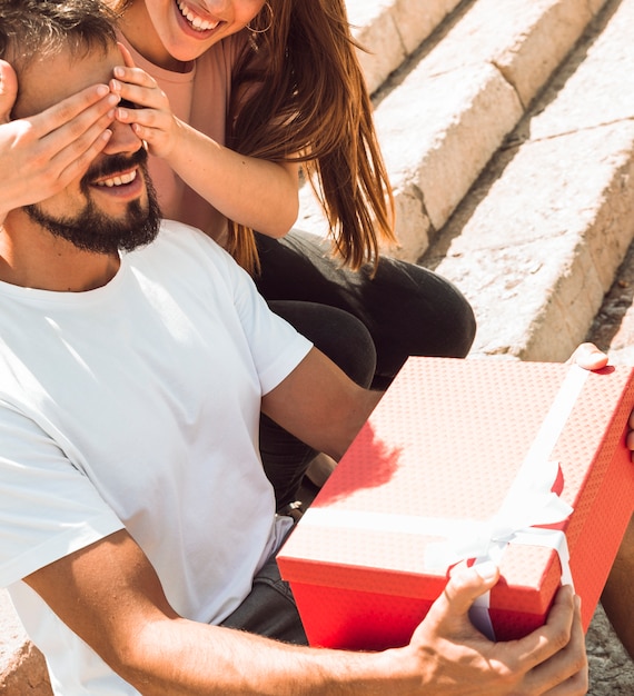 Mujer feliz dando un regalo sorpresa a su novio