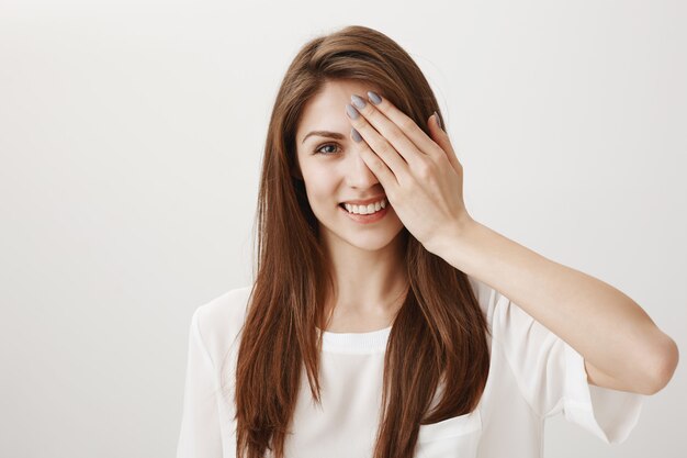 Mujer feliz despreocupada cubre la mitad de la cara y sonriendo complacido