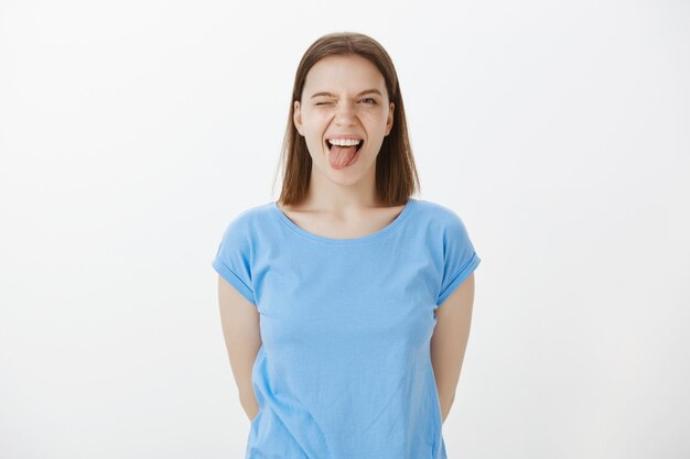 Mujer feliz despreocupada mostrando la lengua y guiñando un ojo alegre