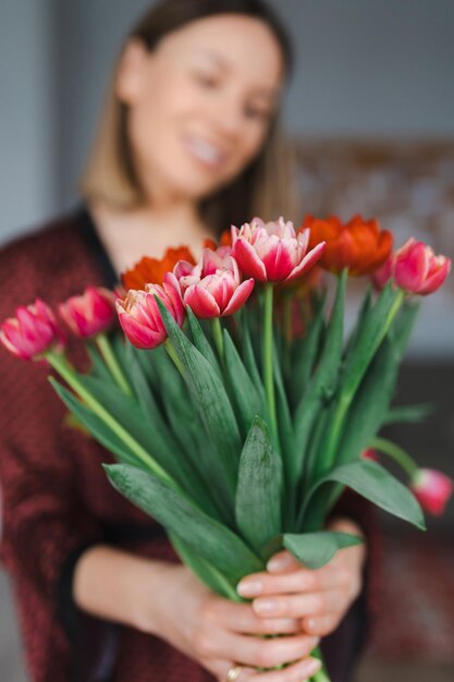 Mujer feliz disfruta de un ramo de tulipanes Ama de casa disfrutando de un ramo de flores y el interior de la cocina Dulce hogar Libre de alergias