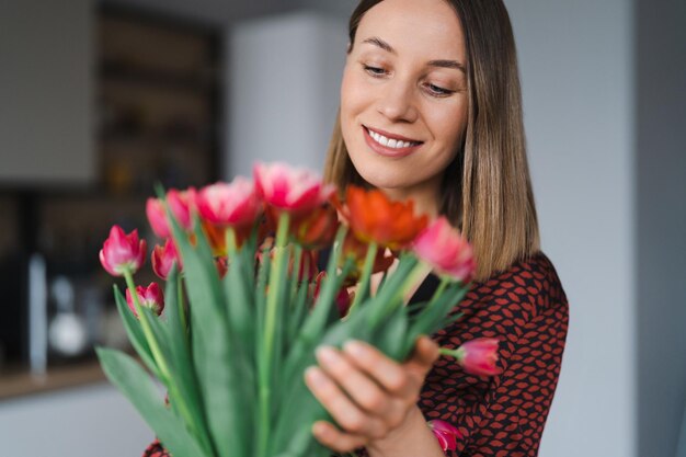 Mujer feliz disfruta de un ramo de tulipanes Ama de casa disfrutando de un ramo de flores y el interior de la cocina Dulce hogar Libre de alergias