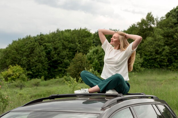 Mujer feliz disfrutando de la naturaleza mientras está encima del coche