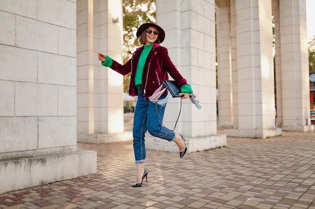 Mujer feliz divirtiéndose en traje de moda estilo otoño caminando en la calle