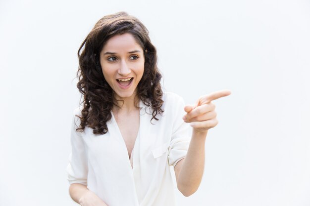 Mujer feliz emocionada que señala el dedo lejos