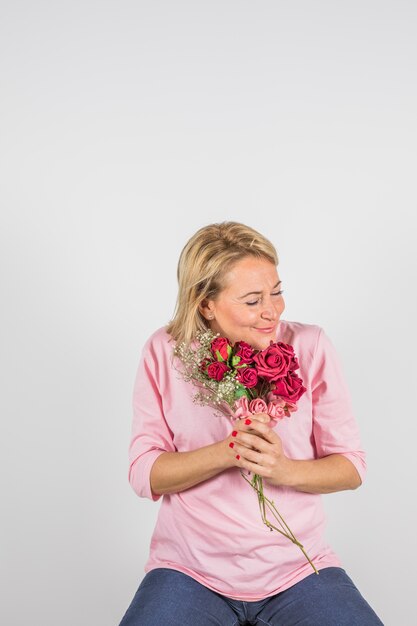 Mujer feliz envejecida en blusa rosa con hermosas flores