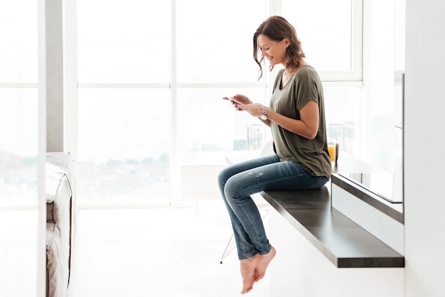 Mujer feliz enviando mensajes de texto en el teléfono móvil