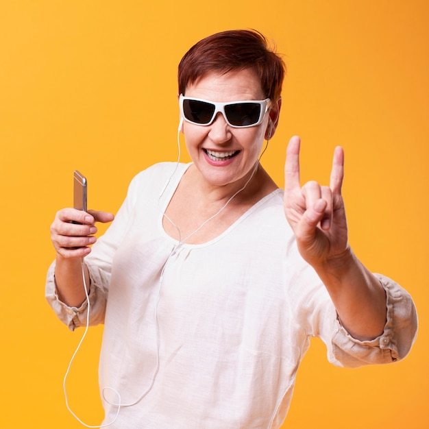 Mujer feliz escuchando música y mostrando el signo de rock