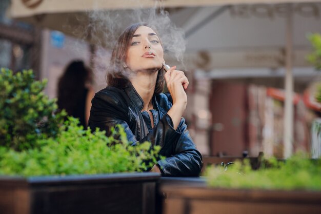 Mujer feliz fumando con un cigarrillo electrónico