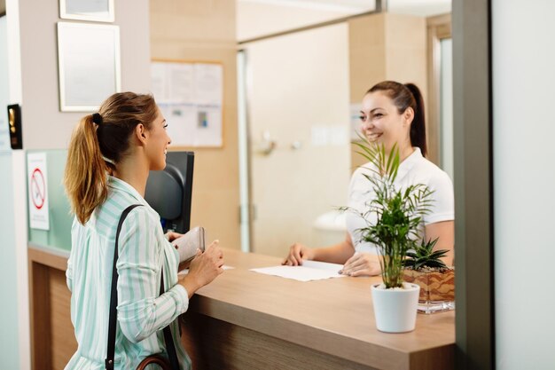 Mujer feliz hablando con una recepcionista al llegar al spa