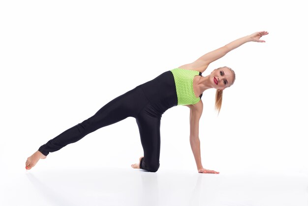 mujer feliz haciendo ejercicio en estudio sonriendo alegremente mientras estira