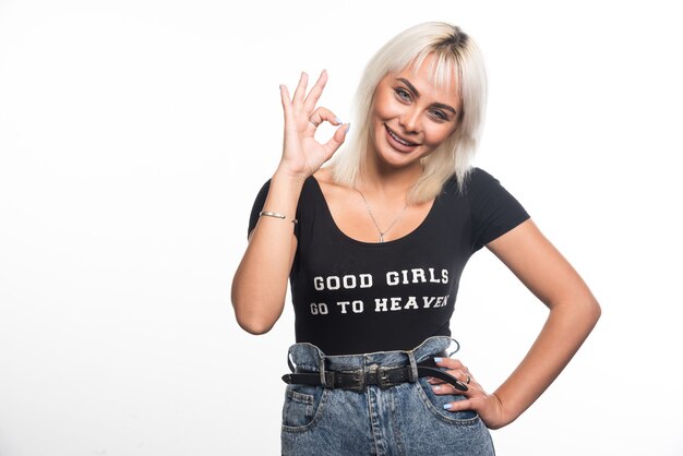 Mujer feliz haciendo el signo de ok en la pared blanca.