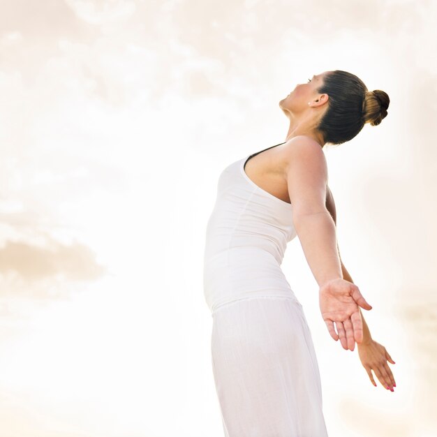 Mujer feliz haciendo yoga bajo el sol