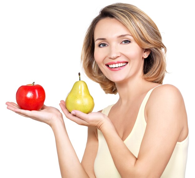 Mujer feliz hermosa joven sostiene la manzana y la pera aislados en blanco.