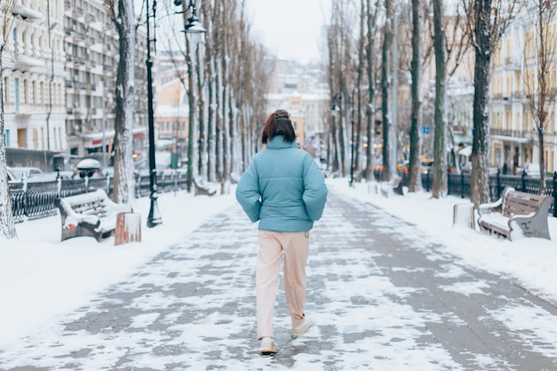 Mujer feliz en invierno en el callejón de la ciudad nevada