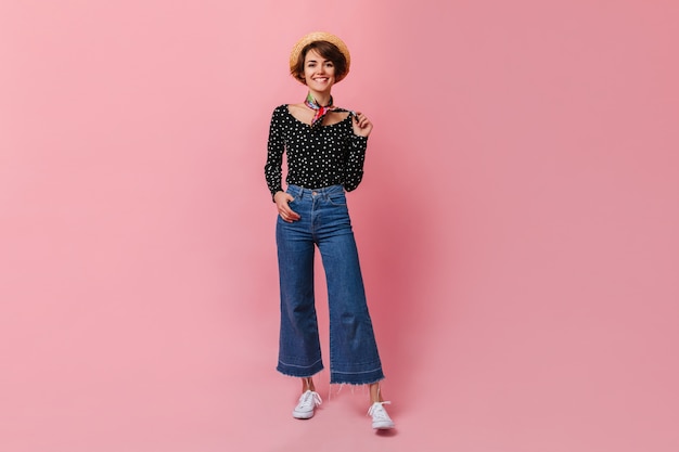 Mujer feliz en jeans vintage en pared rosa