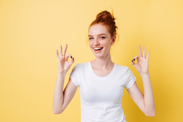 Mujer feliz jengibre mostrando signos bien con ambas manos