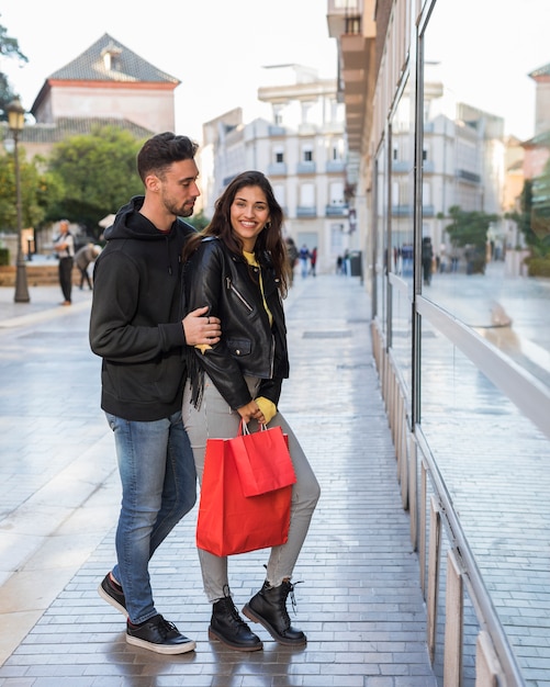 Mujer feliz y joven en la calle cerca de la ventana de la tienda