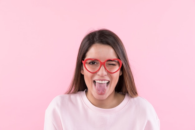 Foto gratuita mujer feliz joven con las lentes que muestran la lengua