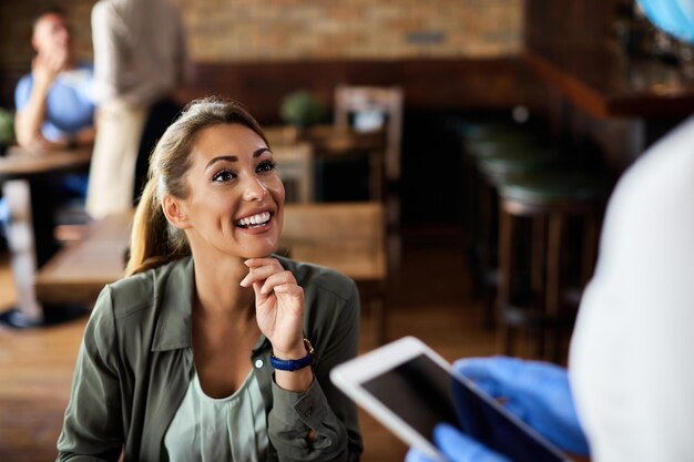 Mujer feliz joven que habla con una camarera en un café